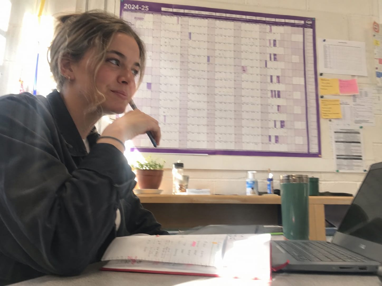 A teacher planning her year against a wall-mounted year planner